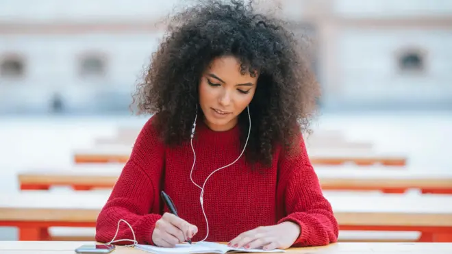 Una mujer con auriculares escribiendo.