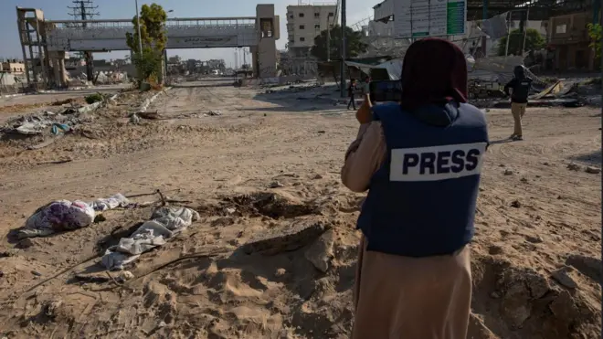 صورة تظهر صحفية وهي تلتقط صورة للدمار 
