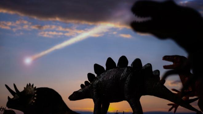 Dinosaurios y un asteroide cayendo en el fondo.
