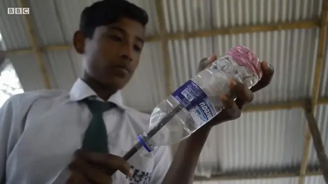 นักเรียนกำลังยัดขยะใส่ขวดพลาสติก