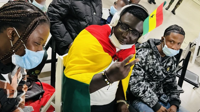 Man put Ghana flag for im head wit headphone, anoda man dey beside am wit nose mask