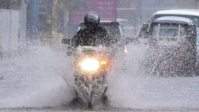 වර්ෂාව මැද ධාවනය කෙරෙන යතුරු පැදියක් 