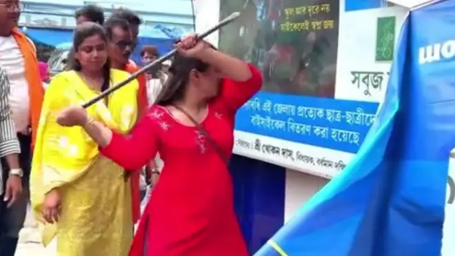 एक बिलबोर्ड को तोड़ती महिला और कई लोग