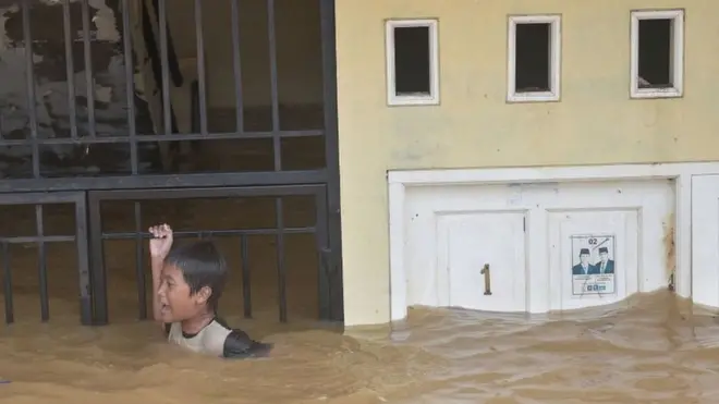 Di depan rumah di kawasan Kampung Melayu, Jakarta Timur, yang terendam banjir, seorang bocah terlihat bermain.