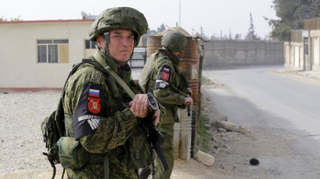 Russian military police members stand guard at the Wafideen checkpoint on the outskirts of the Syrian capital Damascus