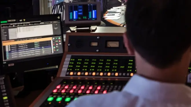 A radio studio sound desk viewed from behind a producer