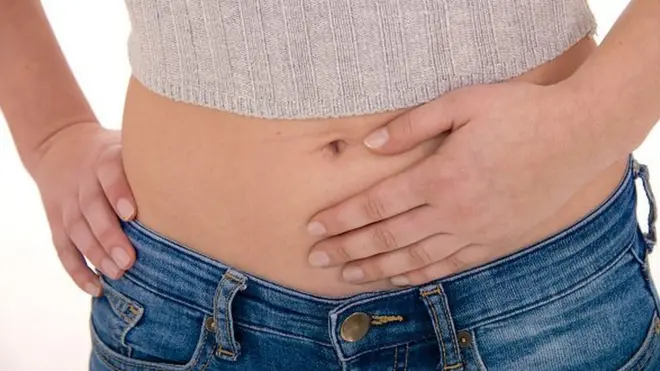 배를 부여잡고 있는 여성