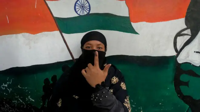 मतदान के बाद उंगली में लगी स्याही दिखाती मतदाता