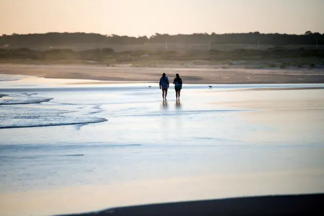 Duas pessoas caminham por uma praia no Uruguai