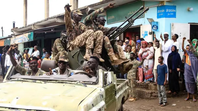 أشخاص يهتفون لأعضاء القوات المسلحة السودانية المشاركين في عرض عسكري أقيم في يوم الجيش في القضارف في 14 أغسطس 2024.