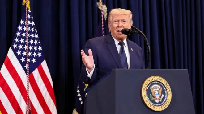 紺の幕と星条旗などを背に、大統領印のついた演台を前にマイクに向かって話す紺色スーツ姿のトランプ氏