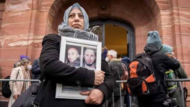 Syrians stood outside the court in Koblenz clutching photos of victims of the civil war