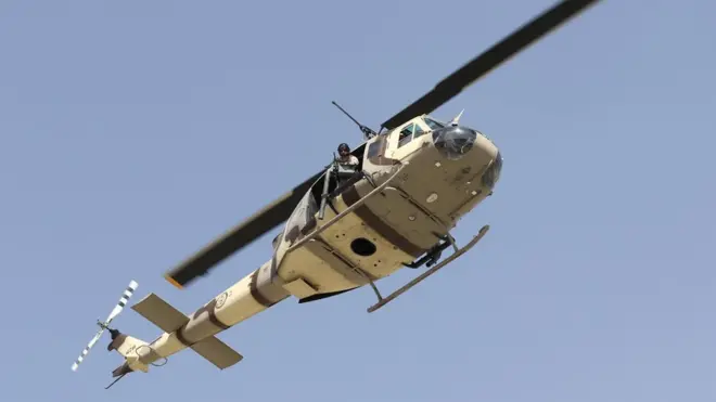 A US UH-1N military helicopter hovers over the scene after six rockets were fired near Kabul airport