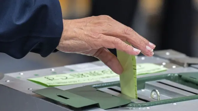 Человек опускает бюллетень в урну