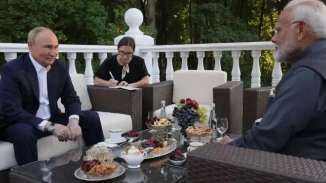 بوتين ومودي في اجتماع على طاولة في شرفة حولها أشجار وعلى الطاولة مأكولات خفيفة وفواكه.