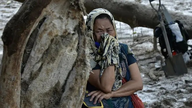 Keluarga korban menangis saat melihat proses pencarian korban banjir bandang di Desa Radda, Kabupaten Luwu Utara, Sulawesi Selatan, Sabtu (18/07).
