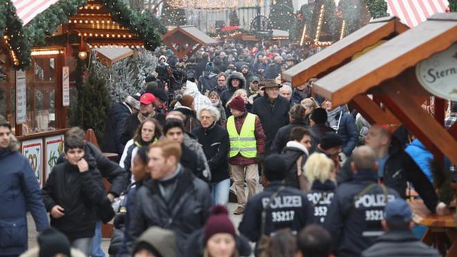 Visiteurs et policiers en marche à la réouverture du marché Breitscheidplatz non loin du lieu de l'attentat au camion