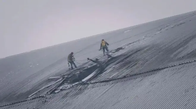 Duas pessoas consertando um buraco no escudo de proteção