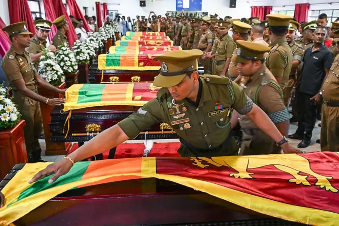 Security personnel pay tribute as they stand next to coffins of seven guards killed during Negombo prison riot in Colombo July 8, 2026. Sri Lanka launched an investigation on July 7 into its deadliest prison riot in years, as the death toll from clashes between rival drug gangs rose to 27. (Photo by Ishara S. KODIKARA / AFP via Getty Images)