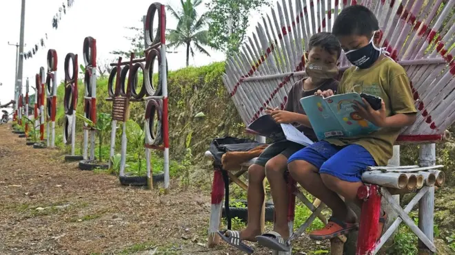 Dua murid sekolah dasar mengikuti proses belajar mengajar secara online di tepi jalan di ruang terbuka supaya bisa mendapat sinyal di Kampung Gunungsari, Serang, Banten, Juli lalu. Sejumlah siswa sekolah di pelosok Banten masih kesulitan mengikuti proses belajar mengajar jarak jauh selama masa pandemi COVID-19 akibat kendala akses sinyal internet serta keterbatasan peralatan dan biaya.