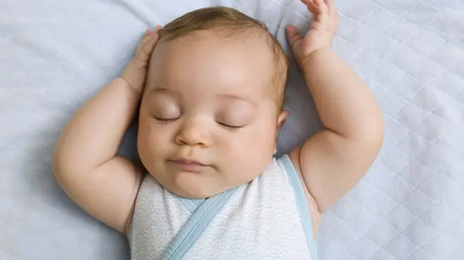 Bebé durmiendo sobre su cama.