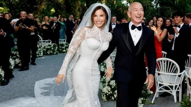 Lauren Sánchez wears a Dolce & Gabbana haute couture gown while Jeff Bezos places his arm around her while wearing a smart black tuxedo
