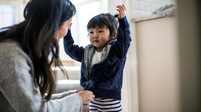 妈妈为孩子挑选衣服这样的家务事就是"母亲把关"的例子，这是一种视为需由妈妈来操持的细微家务（Credit: Getty Images）