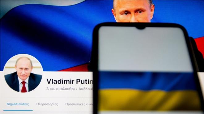 In this photo illustration an Ukraine flag seen displayed on a smartphone screen with Vladimir Putin facebook page in the background in Athens, Greece on February 24, 2022.