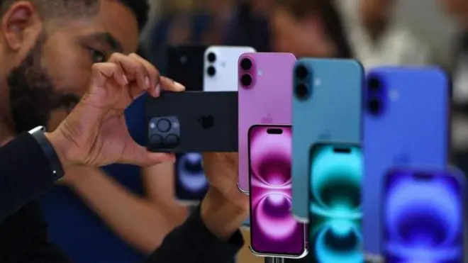 Hombre mirando iPhones en exhibición en una gama de colores azul, verde y morado.