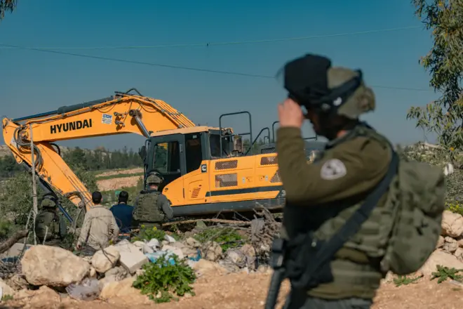جنود إسرائيليون في حالة تأهب بينما تعمل آلة إسرائيلية في أرض في قرية بيت عوا قرب الخليل في الضفة الغربية المحتلة في 5 فبراير/ شباط 2026.