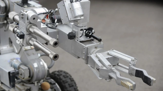 A bomb disposal robot extends its arm