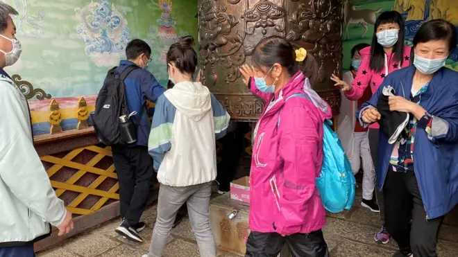 云南一寺庙里戴口罩的游客在转动祷告轮