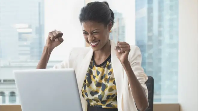 Mulher comemorandojogo de apostas cassinofrente a laptop