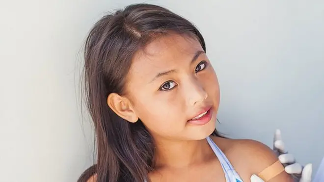 అమ్మాయికి టీకా వేస్తున్న వైద్యురాలు