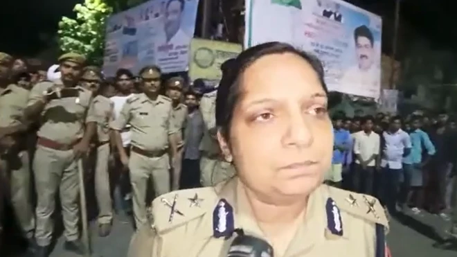 An Uttar Pradesh policewoman speaks to reporters in front of a crowd of police and locals in the district where the girls' bodies were found