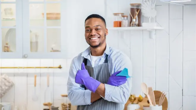 Un homme en gants de nettoyage pose dans sa cuisine