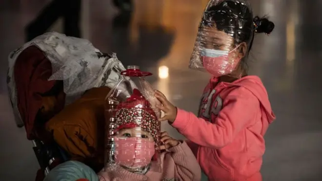 Dua anak di Beijing mengenakan pelindung diri dari botol bekas dan masker saat China mulai diserang wabah Covid-19 akhir Januari lalu.