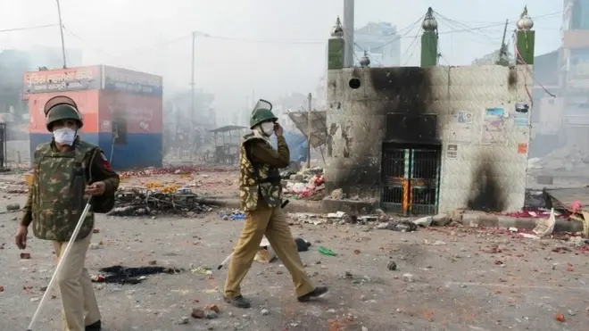Policemen stand on a vandalised road following clashes between supporters and opponents of a new citizenship law, at Bhajanpura area of New Delhi on February 24, 2020, ahead of US President arrival in New Delhi.