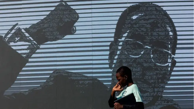 A young boy walks past a digital image of late former Zimbabwean president Robert Mugabe as his body lies in state at Murombedzi Growth Point, about 107 km northwest of Harare, Zimbabwe, on September 16, 2019