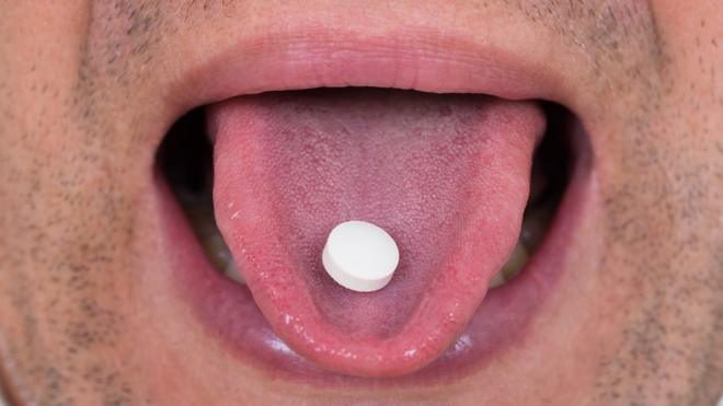 Hombre con una pastilla en la lengua