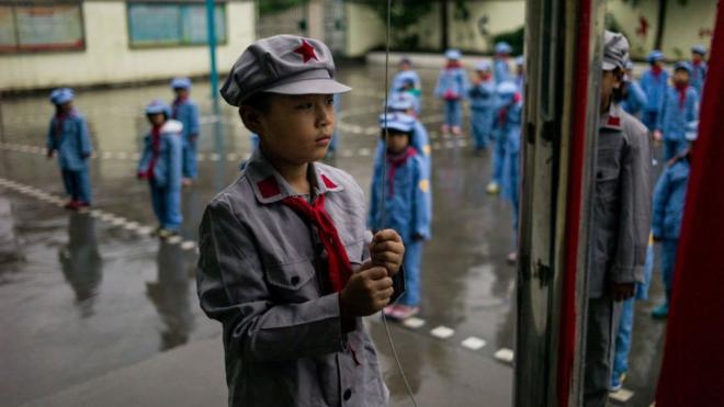 中国一所学校学生身着红军服装升旗。