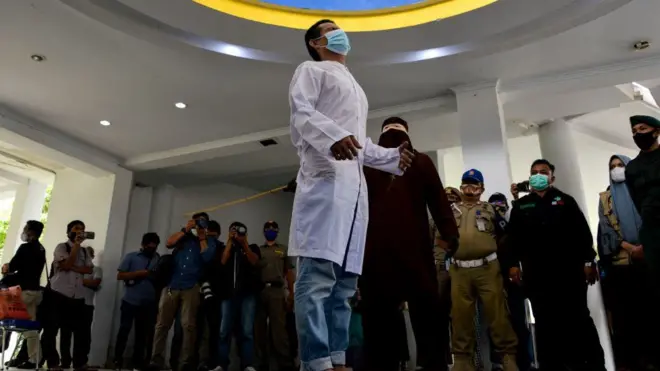 رجل يضرب رجل آخر بالعصا في آتشيه، أندونيسيا