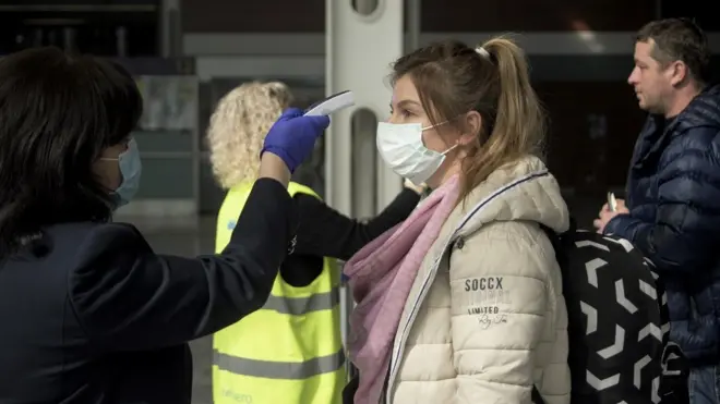 Airport workers and border guards check the body temperatures of arriving passengers at Danylo Halytskyi International Airport in Lviv, Ukraine, 13 March 2020.