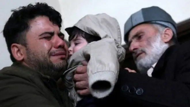 Hamid Safi, a 29-year-old taxi driver who had found baby Sohail Ahmadi in the airport, cries as he hands over Sohail to his grandfather
