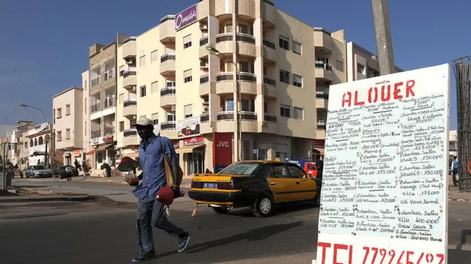 une affiche indiquant "A louer" devant un immeuble vide dans un quartier résidentiel de Dakar.