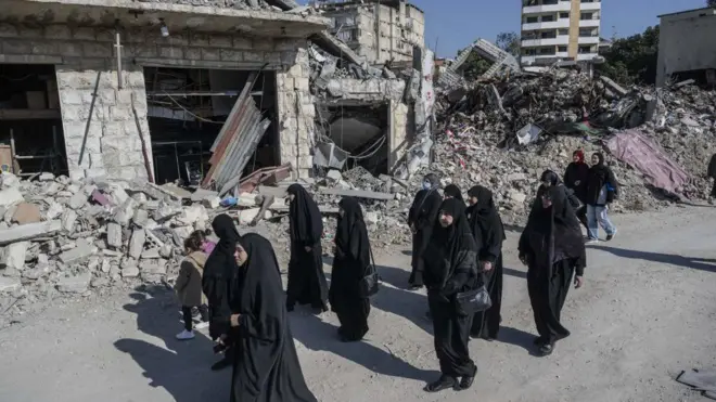 سيدات لبنانيات يسرن بالقرب من المباني المدمرة بعد الهجمات الإسرائيلية على المنطقة، بينما حيث يعود اللبنانيون إلى منازلهم بعد اتفاق وقف إطلاق النار بين لبنان وإسرائيل في لبنان في 2 ديسمبر/كانون الأول 2024.
