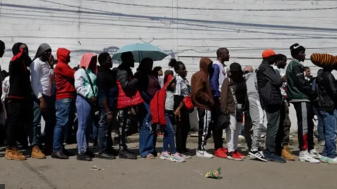 File picture of immigrants standing on a queue 