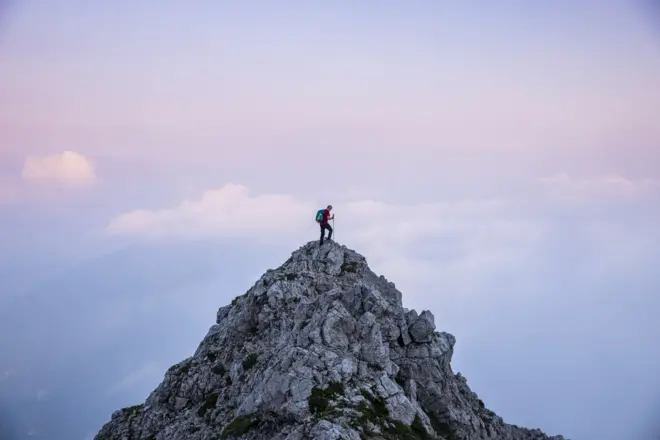 Hiker at the top of an isolated craggy peak 