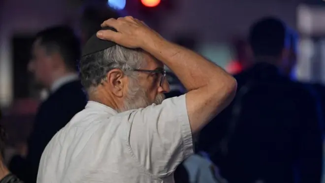 Un hombre con kipá se lleva la mano a la cabeza.