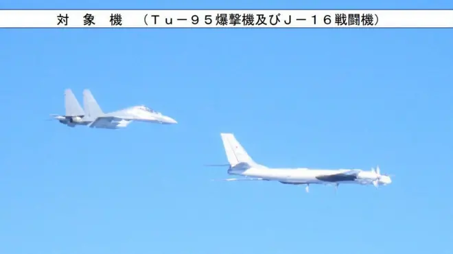 Два самолета в голубом небе, один из них с красной звездой на хвосте, над ними надпись на японском языке с вкраплением слов "Tu-95" и "J-16"